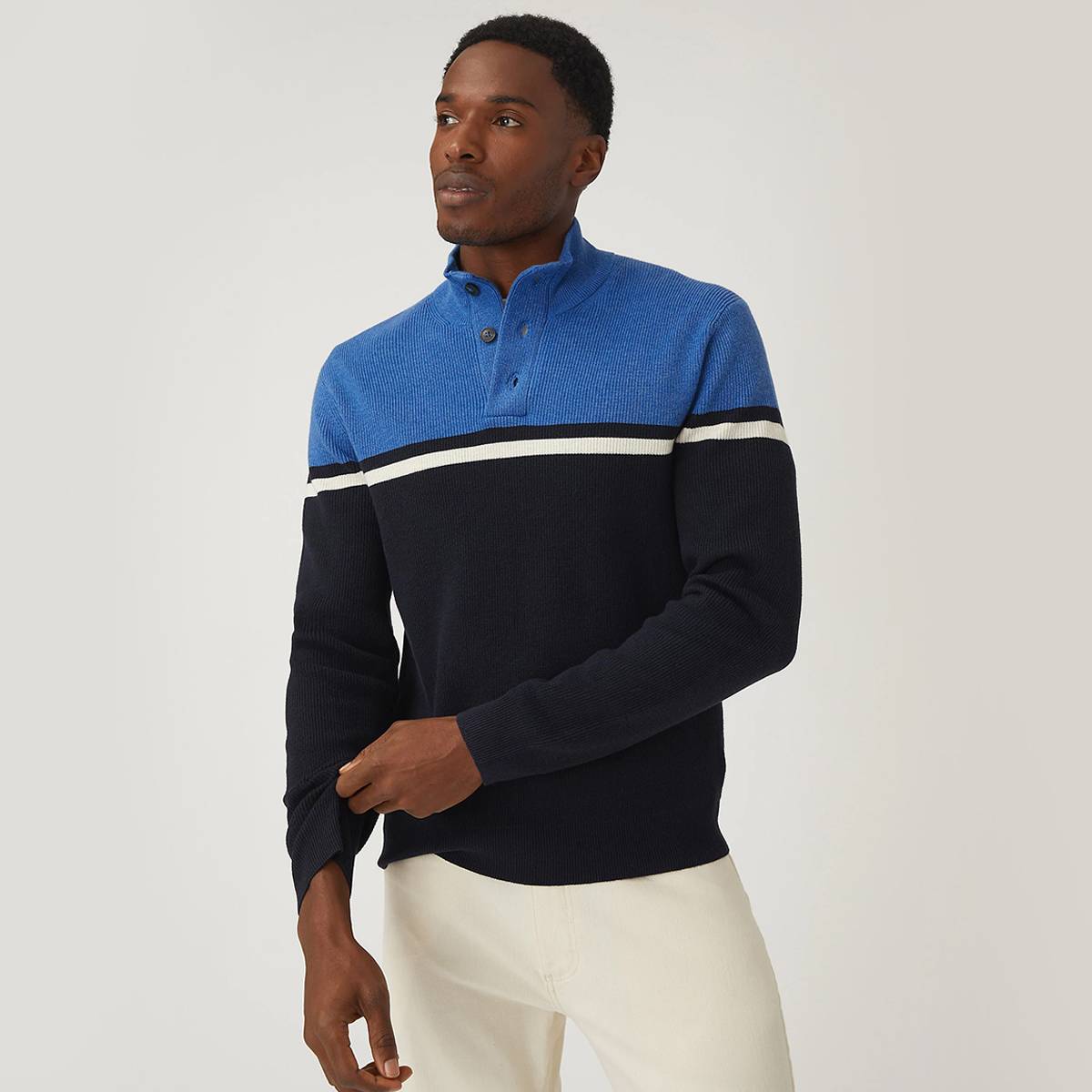 Model wearing a blue and black high-neck jumper. Shop knitwear